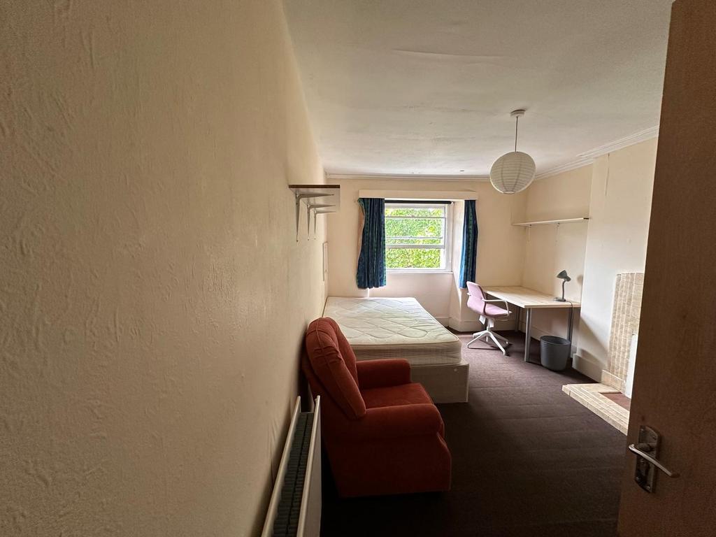Bright furnished bedroom with a large window, c...