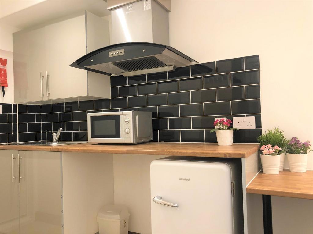 A modern kitchen featuring sleek black tiled ba...