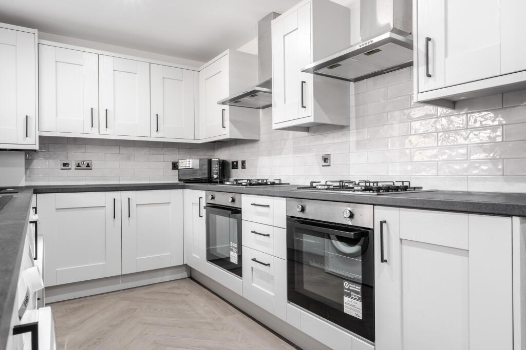 Modern fitted kitchen with matching white cabin...