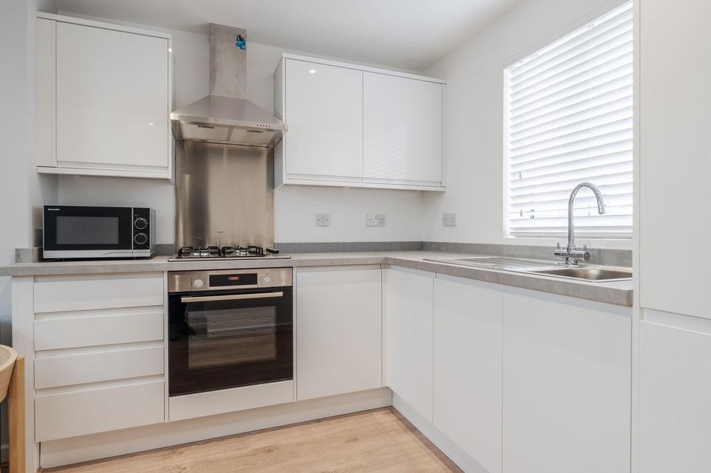 Bright and modern kitchen with white cabinetry,...