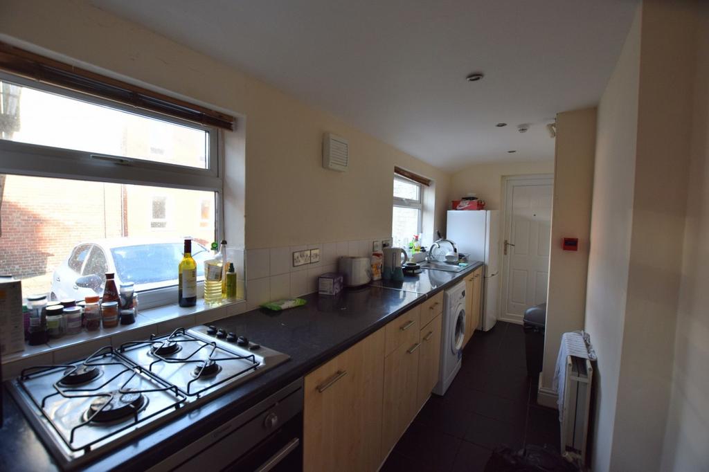 Long galley kitchen with light wood cabinets, d...