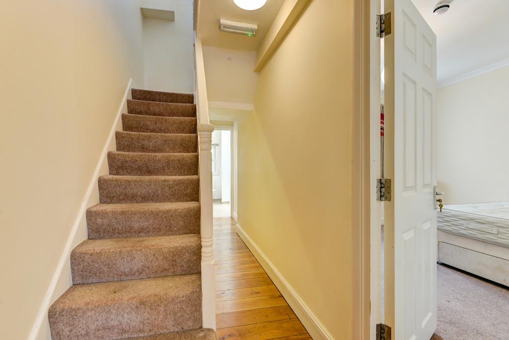 Bright, neutral hallway with wood flooring, car...