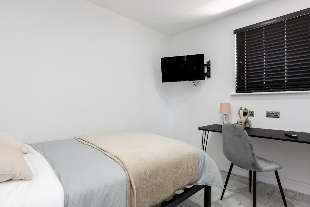 A bright and tidy student bedroom featuring a c...