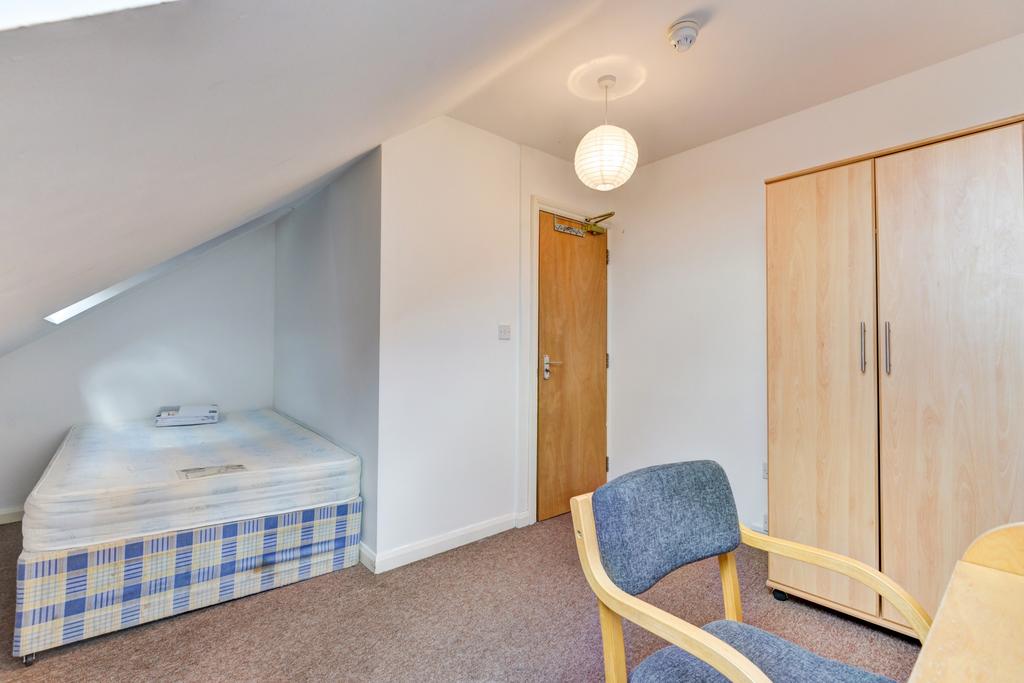 Cozy attic-style single bedroom with a neatly m...