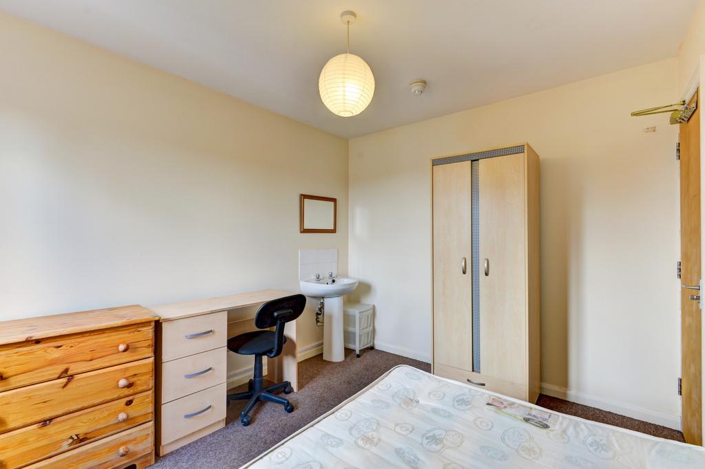 A bright and tidy bedroom featuring a wardrobe,...