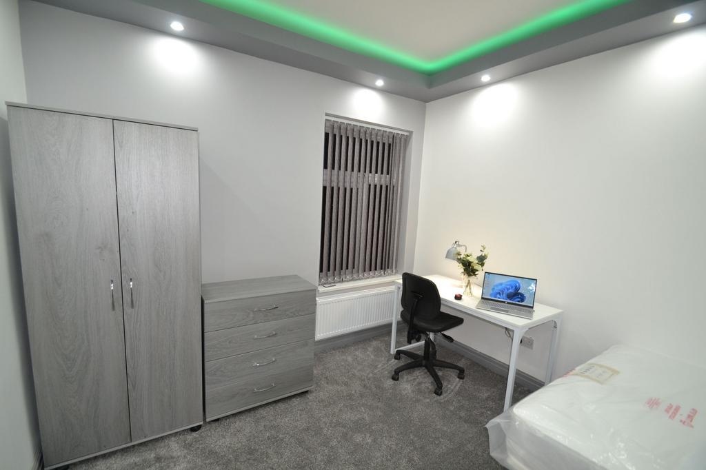 A bright and tidy student room featuring a stud...