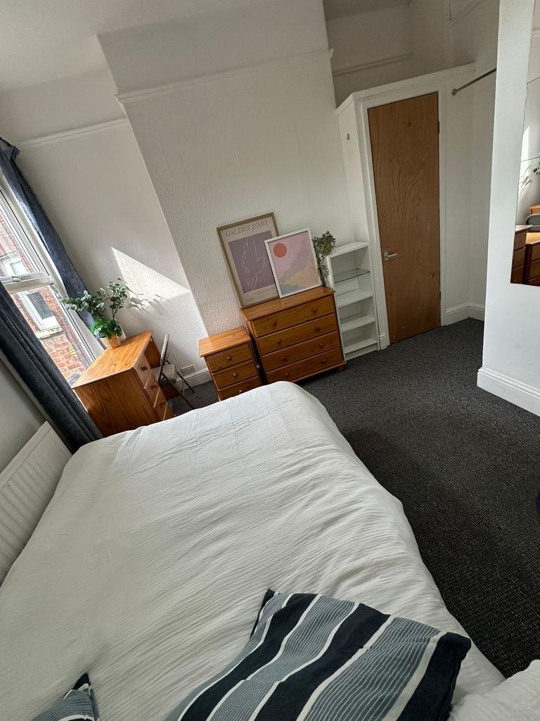 A cozy bedroom featuring a neatly made bed, nat...