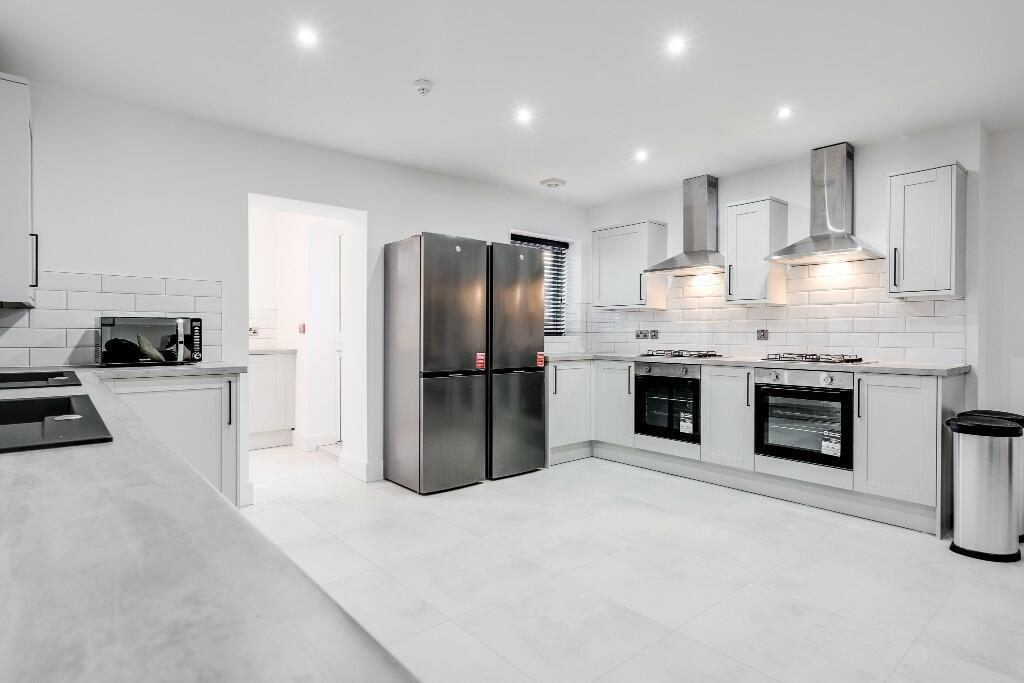 A bright, modern kitchen featuring sleek white ...