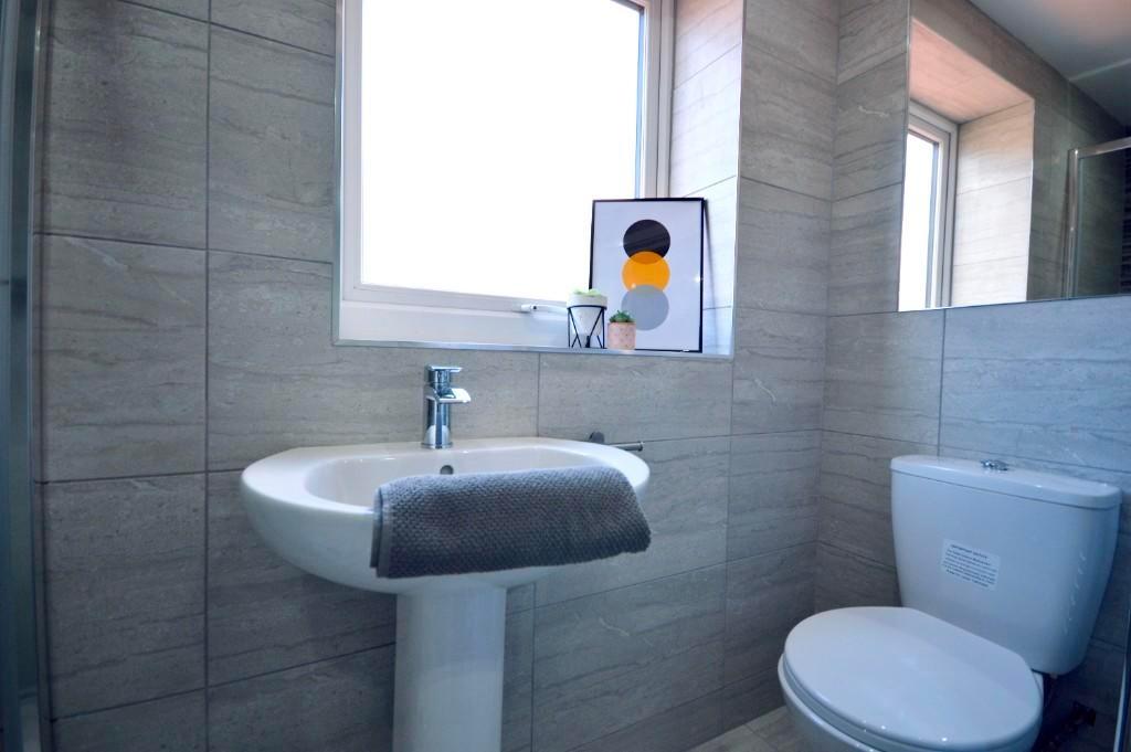A tidy bathroom with a modern toilet, a sink wi...