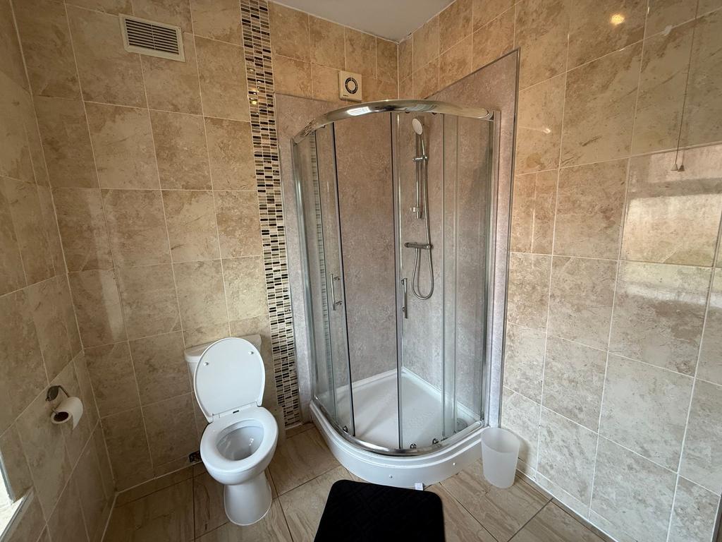 Bright, tiled bathroom with a modern corner sho...