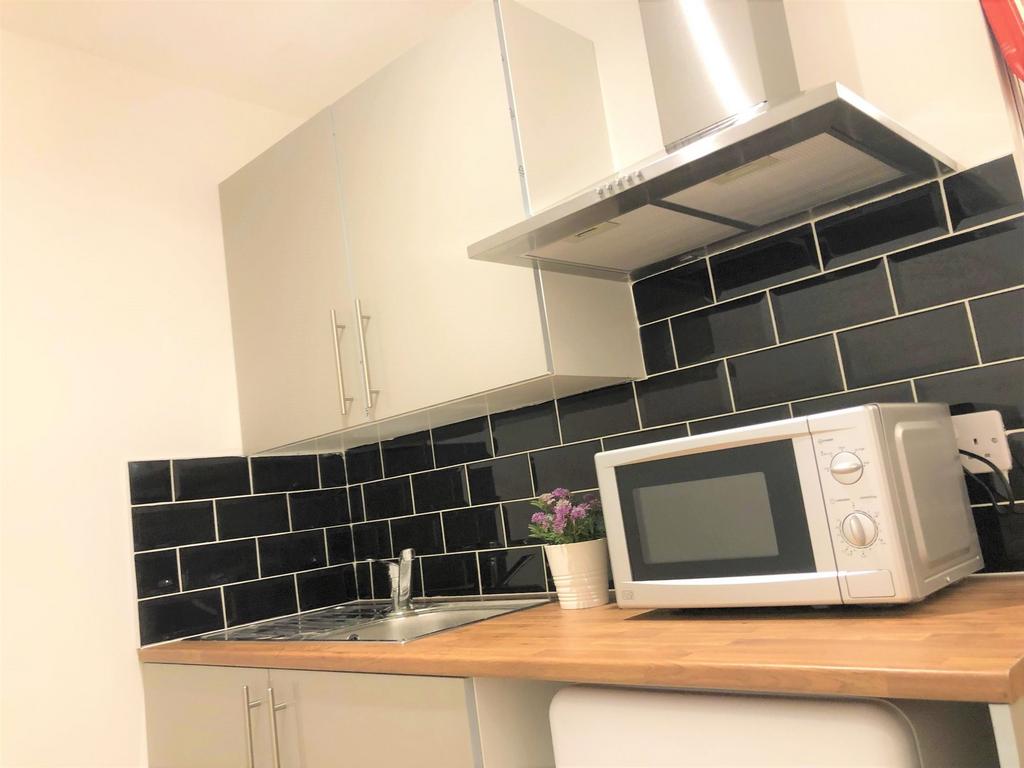 A modern kitchen featuring sleek black tiled ba...