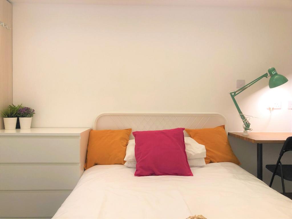 A cozy and tidy single bedroom featuring a comf...