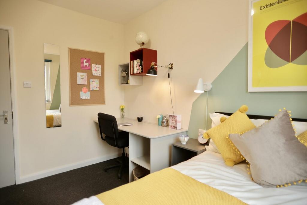 A bright and cozy bedroom featuring a neatly ma...