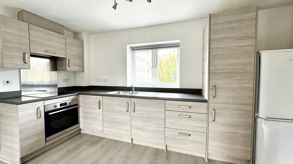 Modern fitted kitchen with light wood cabinets,...