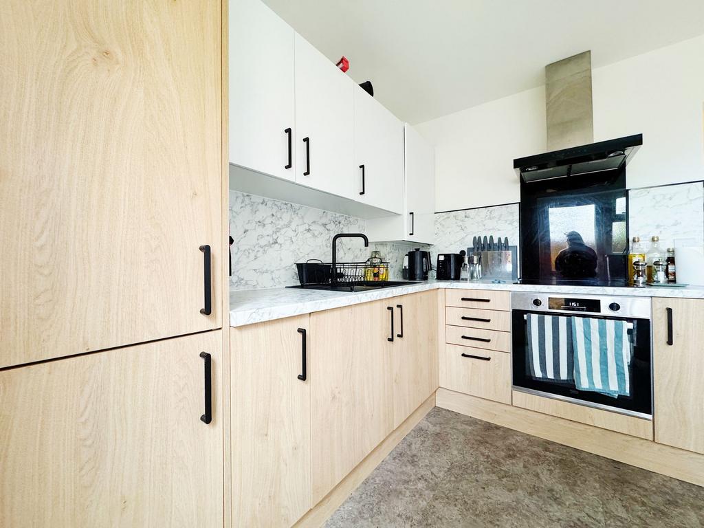 Modern L-shaped kitchen with light wood lower c...
