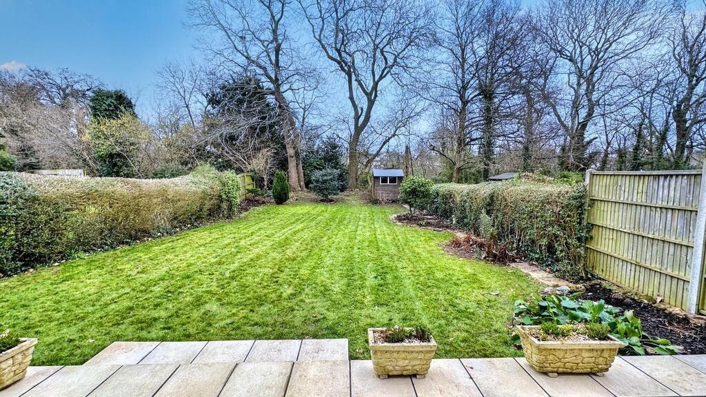 Well-maintained rear garden with a neat lawn, p...