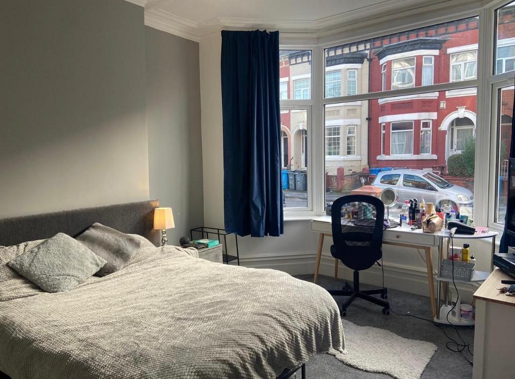 A well-lit bedroom featuring a comfortable doub...