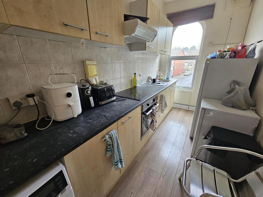 Bright galley kitchen with light wood cabinets,...