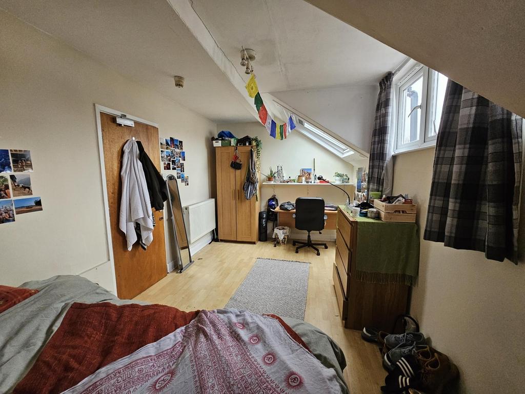 Bright single bedroom with a large window, stud...