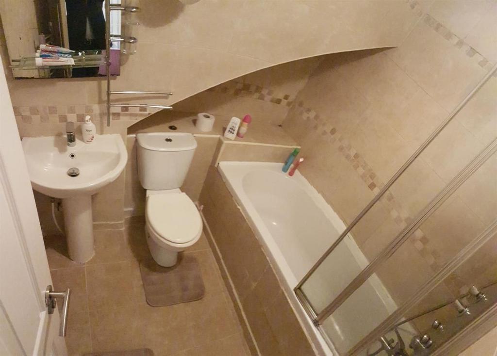 Neat, neutrally tiled bathroom with a bathtub a...