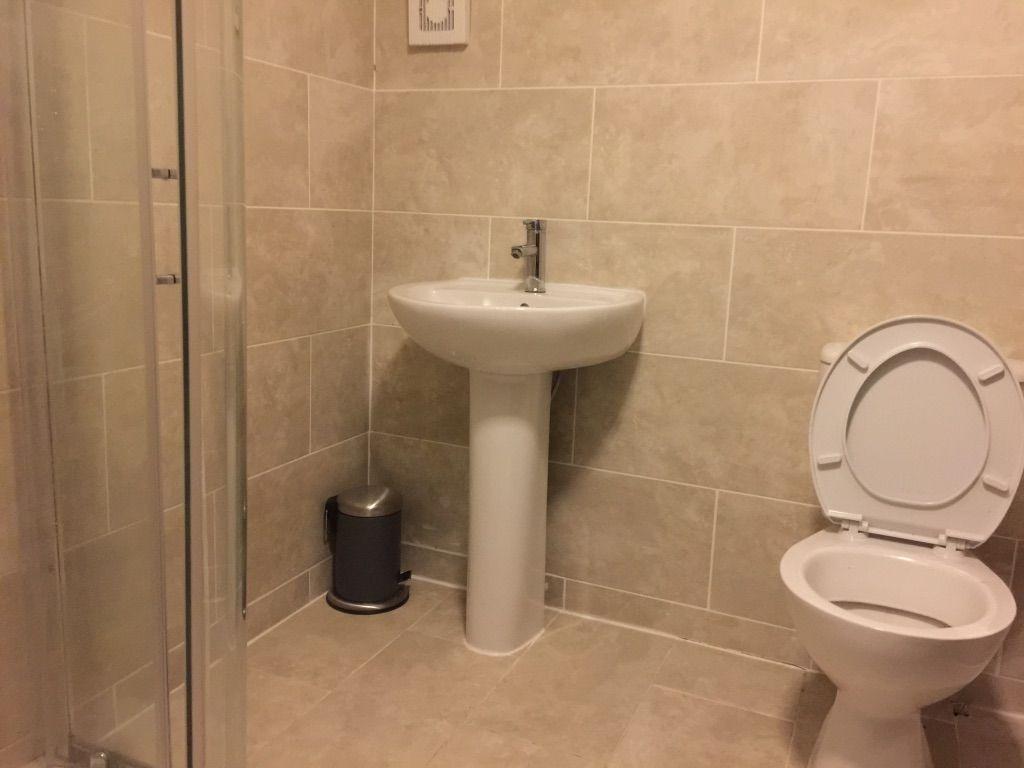 Neutral tiled bathroom with a pedestal sink, en...