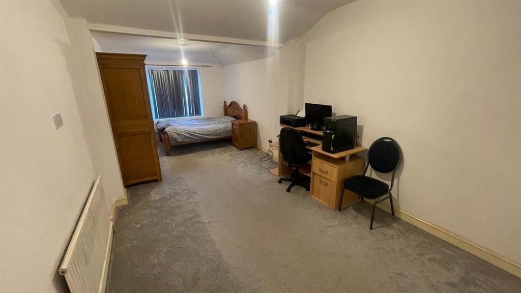 Long, bright single bedroom with a bed at the f...