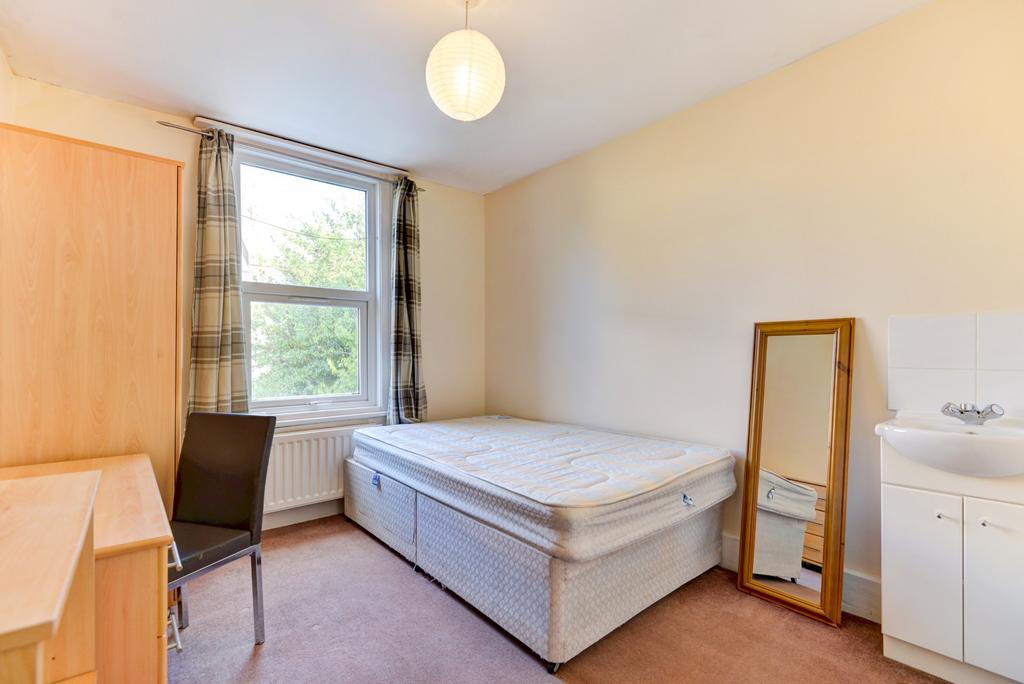 A tidy bedroom featuring a large window, a comf...