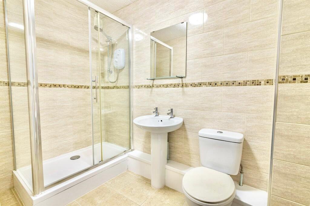 Modern tiled bathroom with a glass-enclosed sho...