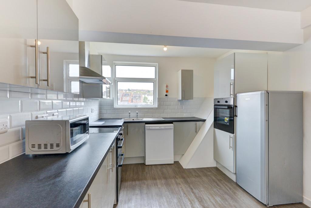 Bright, modern kitchen with white cabinetry, in...