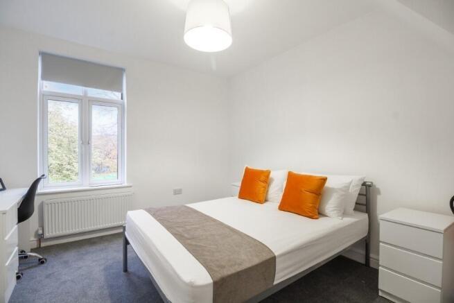 A bright and tidy bedroom featuring a comfortab...
