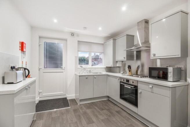 A bright and modern kitchen featuring white cab...