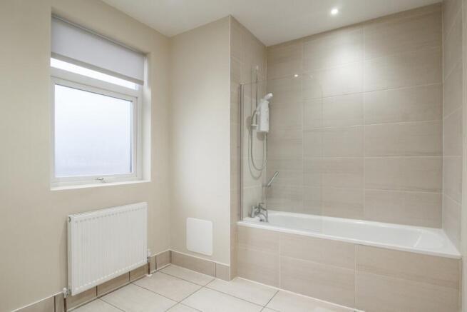 A modern, clean bathroom featuring a bathtub wi...