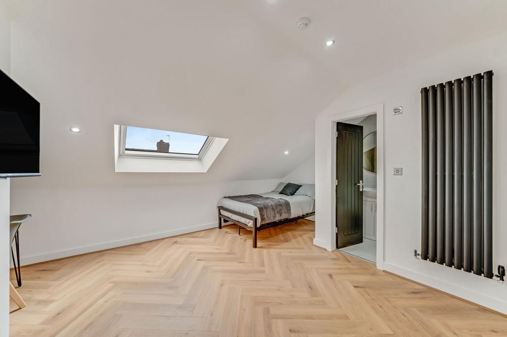 Bright and spacious master bedroom with a skyli...