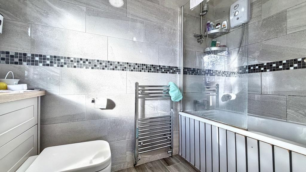 Modern bathroom with tiled walls, a bathtub wit...
