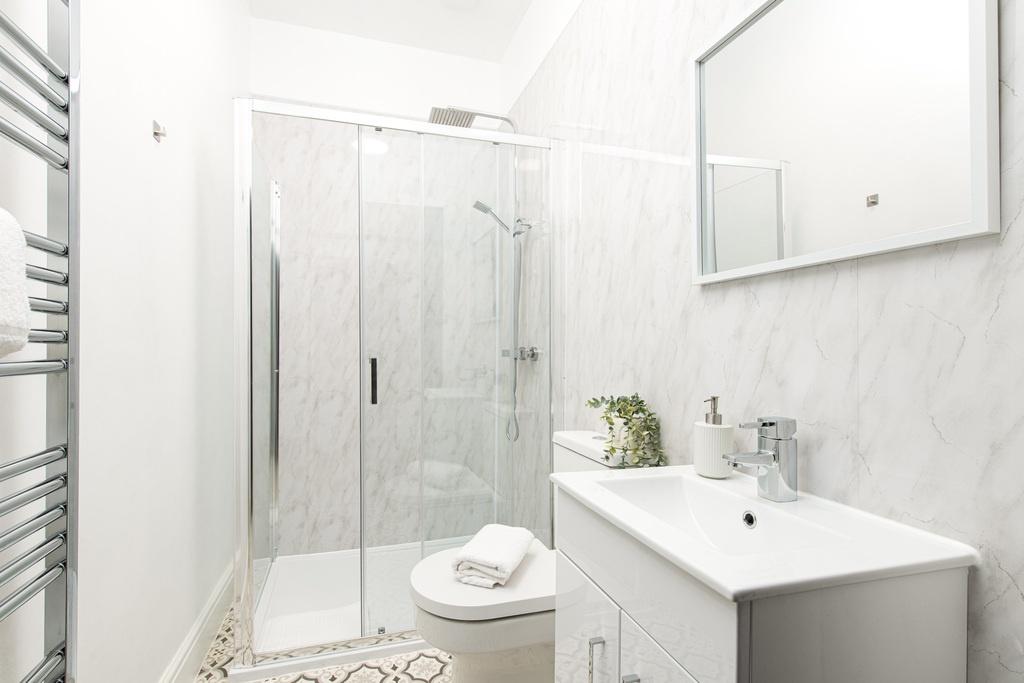 Modern white bathroom with a glass-enclosed sho...