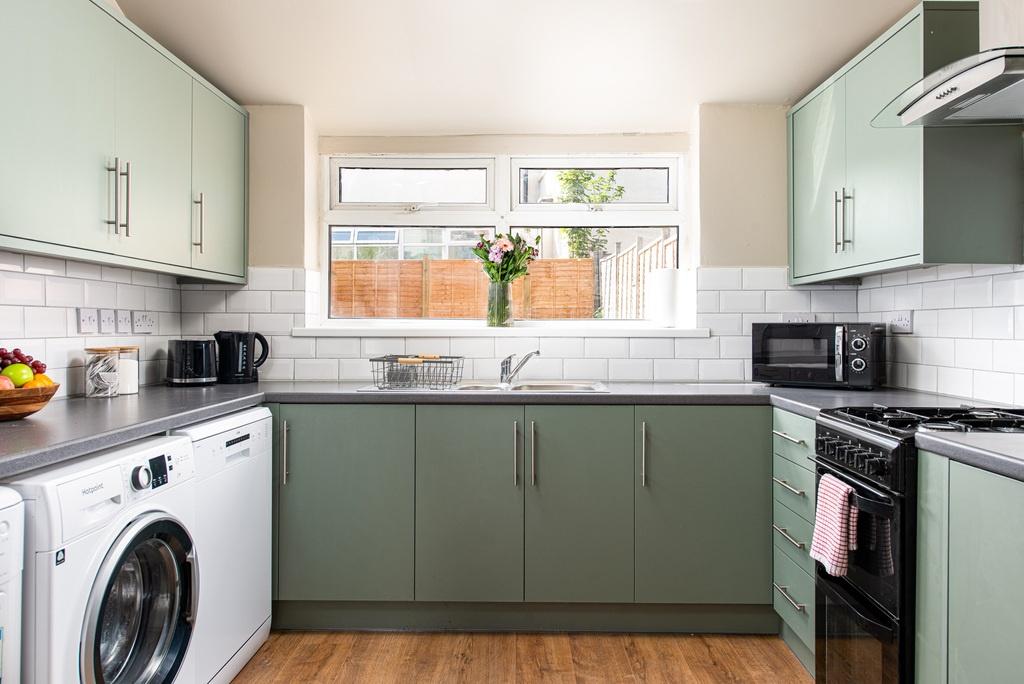 Modern galley kitchen with sage-green lower cab...