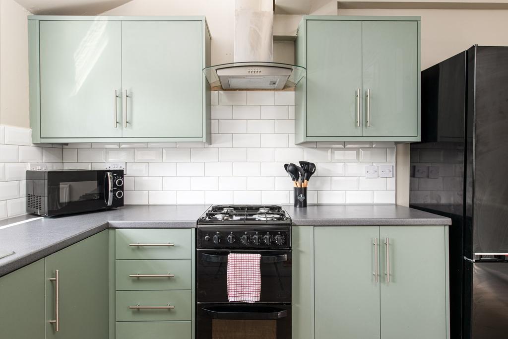 Well-presented modern kitchen with sage-green f...