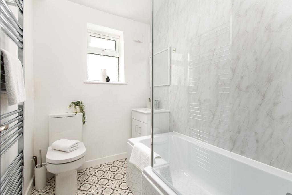 Bright, modern bathroom with a white bathtub an...