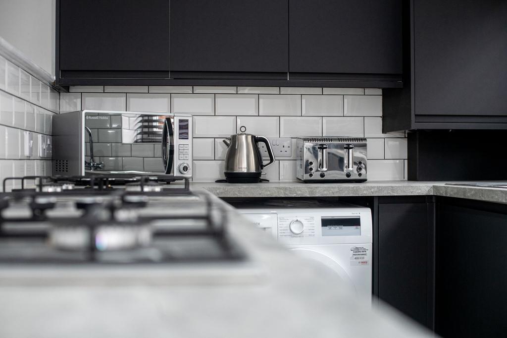 Modern kitchen with sleek black cabinets, a mic...