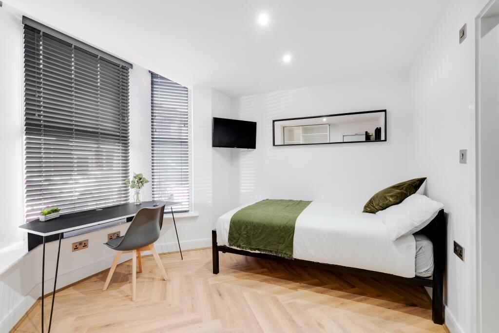 A cozy single bedroom featuring a comfortable b...