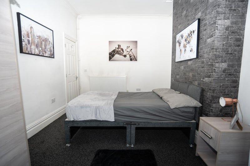 Neat, modern double bedroom with a dark upholst...