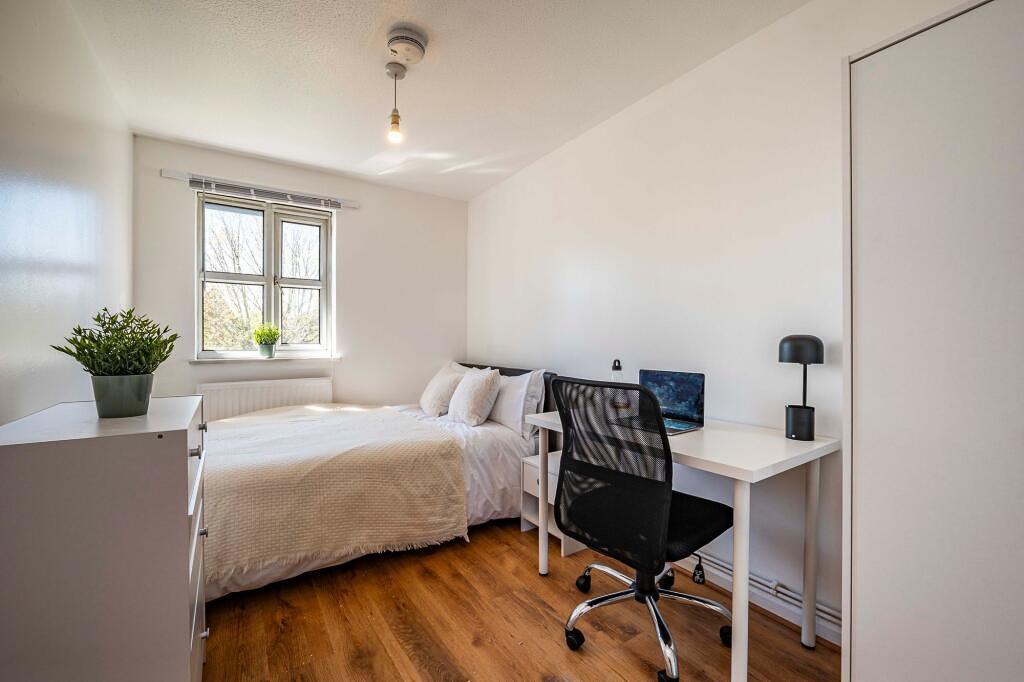 Bright, neatly furnished bedroom with a comfort...