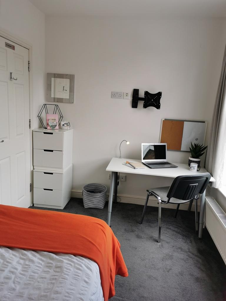 Bright, neatly arranged bedroom with a study co...