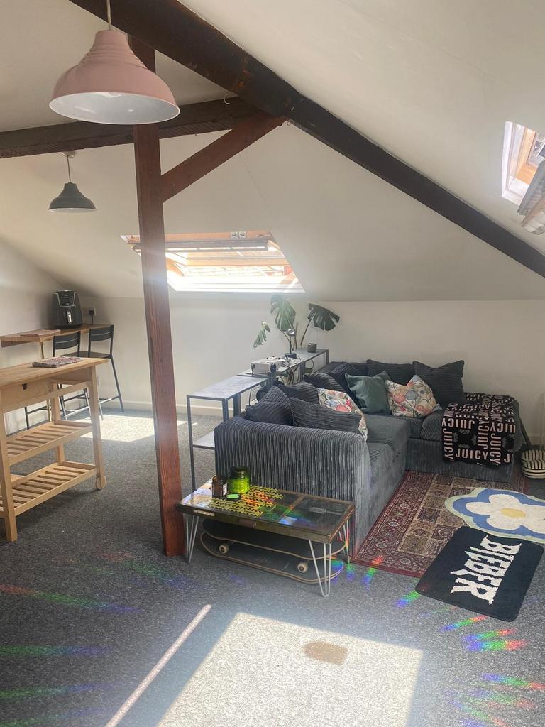 Bright, loft-style living area with exposed bea...