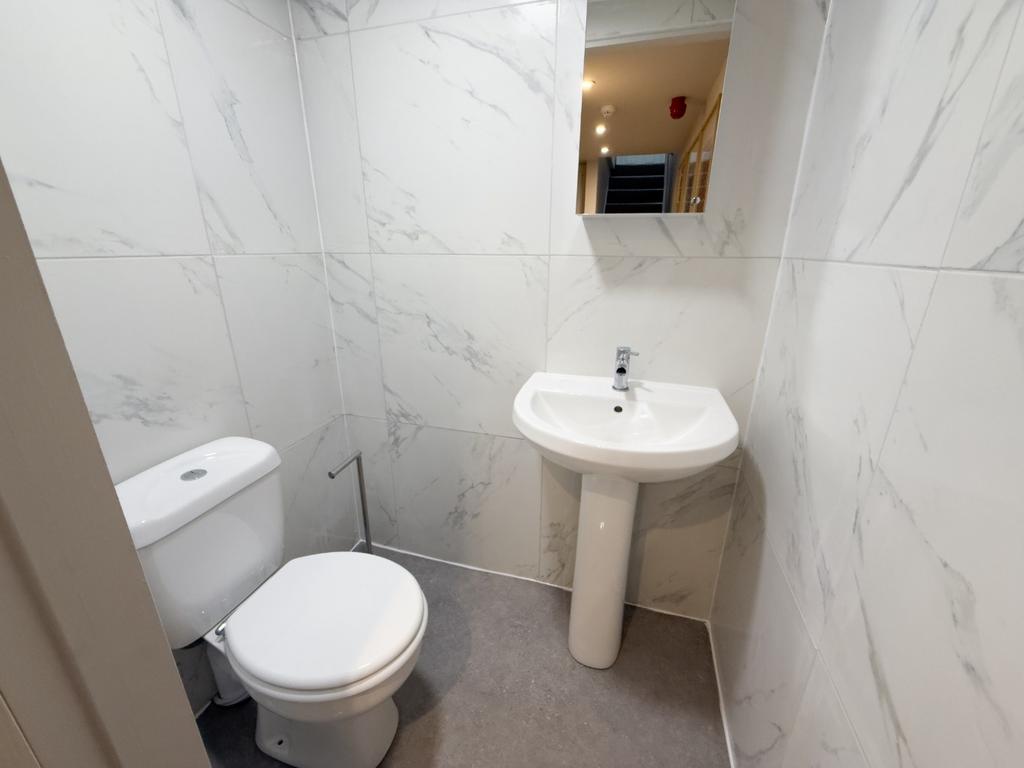 Compact, modern bathroom with white marble-effe...