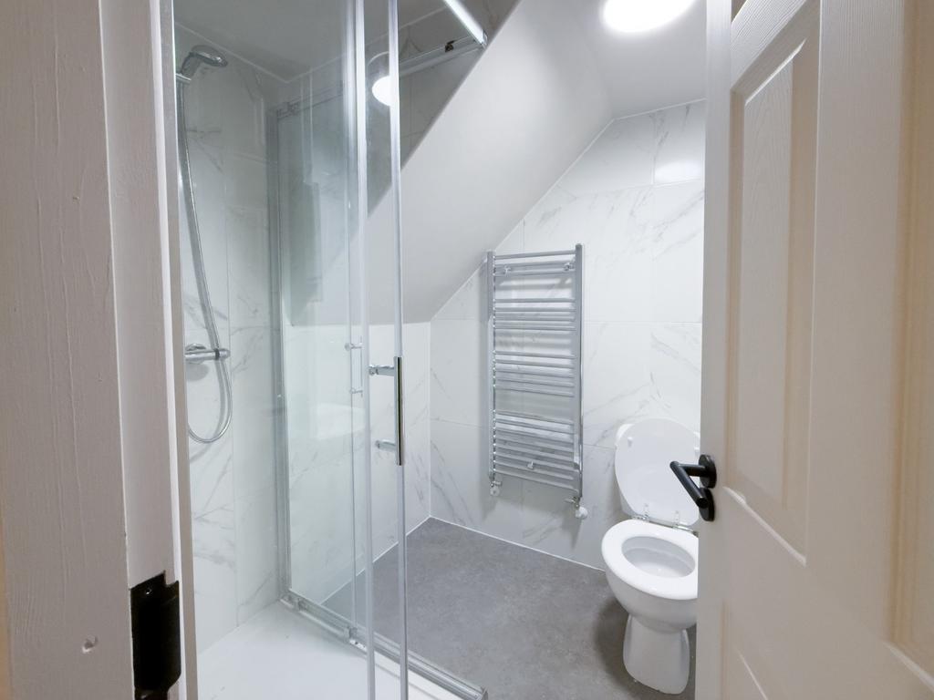 Modern white bathroom with a glass-enclosed sho...