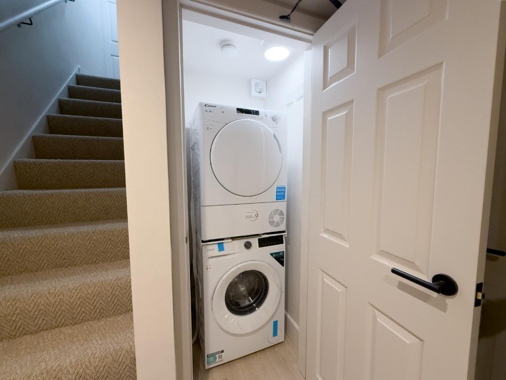 Neat utility cupboard with a stacked washer and...