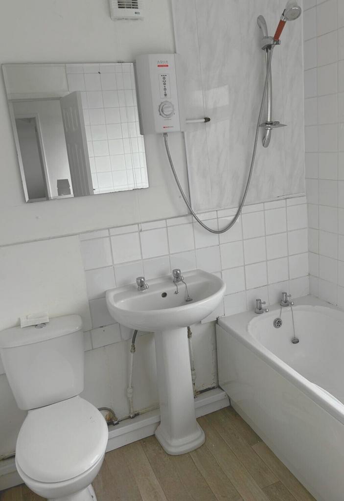 Bright white bathroom with a pedestal sink, bat...