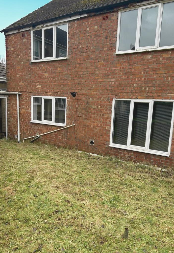 Rear garden with a lawn area bordered by a bric...