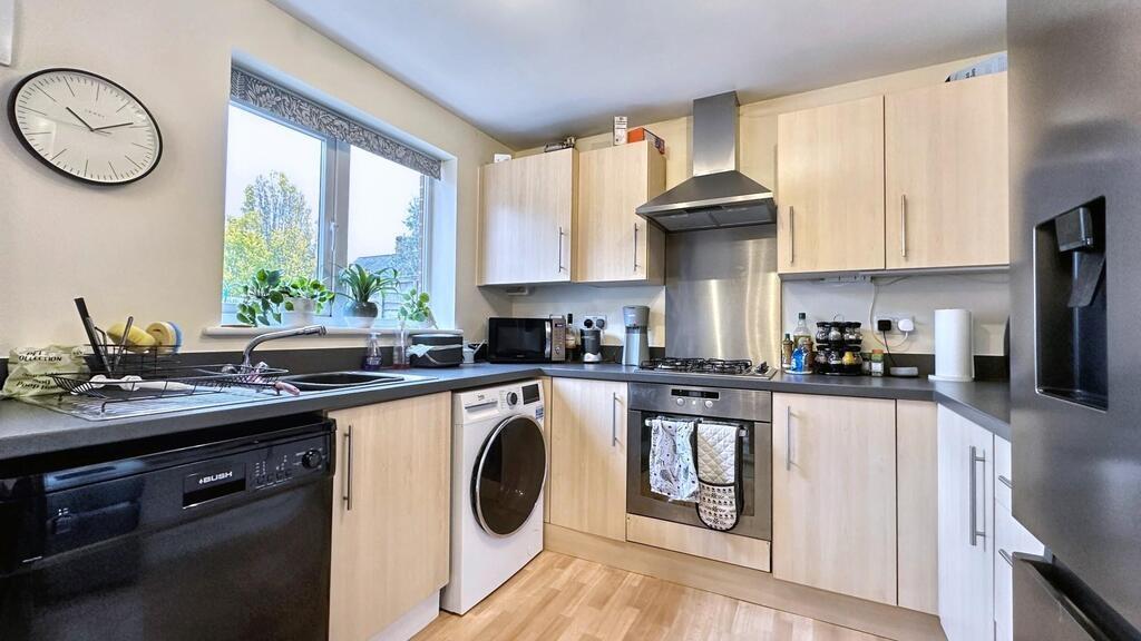 Bright modern kitchen with light wood cabinets,...